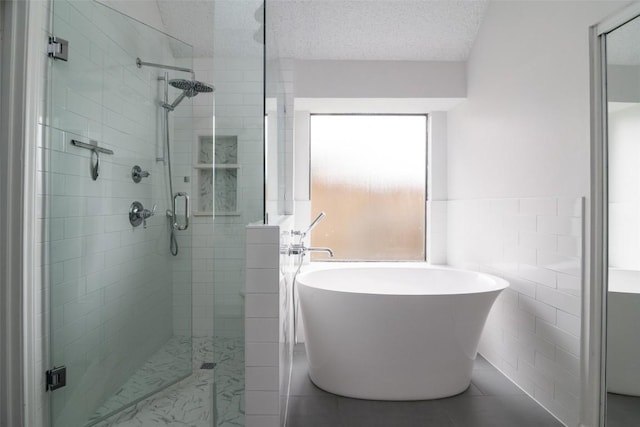 2306 Susan Ln, Leander, TX 78641 - bathroom with a freestanding tub, a stall shower, tile walls, a textured ceiling, and tile patterned flooring