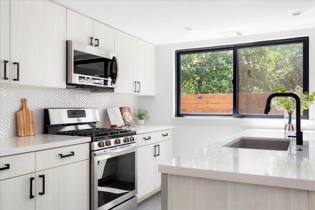 409 W 55th 1/2 St Unit 2, Austin, TX 78751 - kitchen featuring appliances with stainless steel finishes, tasteful backsplash, light countertops, and white cabinetry