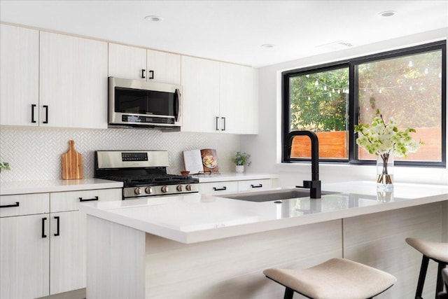 409 W 55th 1/2 St Unit 2, Austin, TX 78751 - kitchen with stainless steel appliances, a breakfast bar area, decorative backsplash, light countertops, and a center island with sink