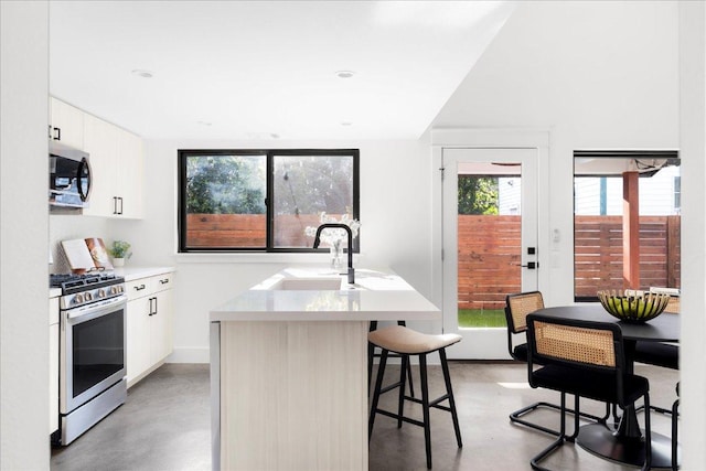 409 W 55th 1/2 St Unit 2, Austin, TX 78751 - kitchen with stainless steel appliances, concrete floors, a kitchen bar, a center island with sink, and white cabinets