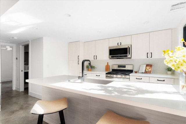 409 W 55th 1/2 St Unit 2, Austin, TX 78751 - kitchen with appliances with stainless steel finishes, decorative backsplash, a kitchen bar, and concrete floors