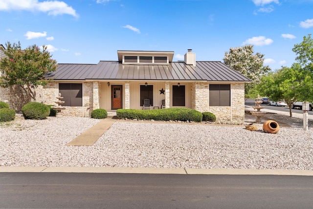 1108 Hi Stirrup Unit 12, Horseshoe Bay, TX 78657 - view of front of house with a standing seam roof, stone siding, a metal roof, covered porch, and a chimney