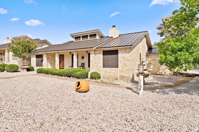 1108 Hi Stirrup Unit 12, Horseshoe Bay, TX 78657 - view of front of house with a chimney, a standing seam roof, a metal roof, stone siding, and a porch