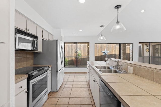 1108 Hi Stirrup Unit 12, Horseshoe Bay, TX 78657 - kitchen with appliances with stainless steel finishes, tile countertops, white cabinetry, hanging light fixtures, and light tile patterned flooring