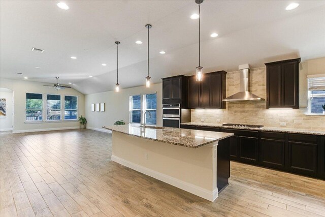 18211 Winnow Way, Pflugerville, TX 78660 - kitchen featuring wall chimney exhaust hood, appliances with stainless steel finishes, a ceiling fan, vaulted ceiling, and tasteful backsplash