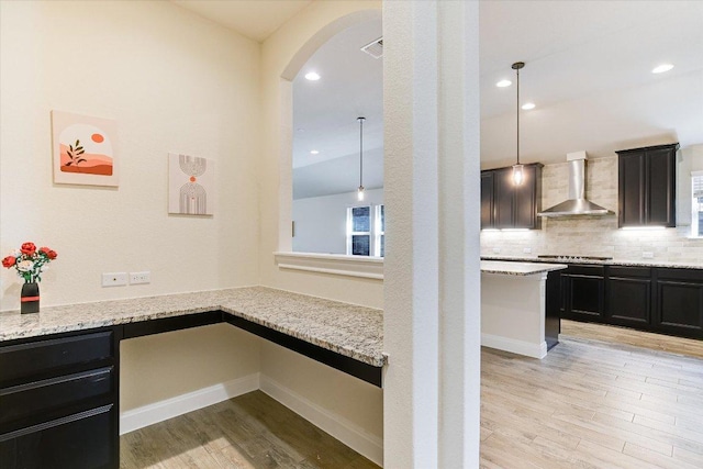 18211 Winnow Way, Pflugerville, TX 78660 - kitchen with wall chimney range hood, light wood-style flooring, arched walkways, light stone countertops, and recessed lighting