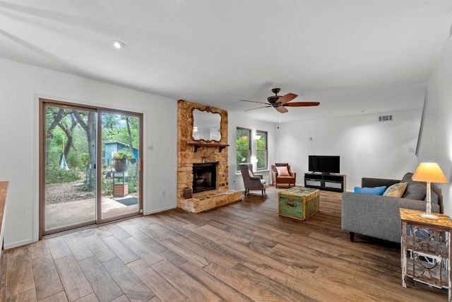 4304 Adelphi Ln, Austin, TX 78727 - living room featuring wood finished floors, plenty of natural light, a stone fireplace, and a ceiling fan