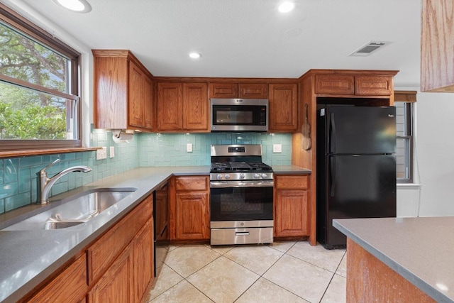 4304 Adelphi Ln, Austin, TX 78727 - kitchen featuring black appliances, light tile patterned floors, brown cabinets, backsplash, and recessed lighting