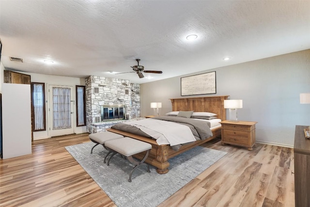 10745 Rosemar Ln, Adkins, TX 78101 - bedroom with light wood-style flooring, a fireplace, a textured ceiling, ceiling fan, and recessed lighting