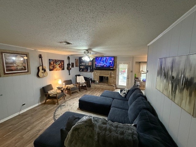 410 Phoenix Dr, Temple, TX 76504 - living room with wood finished floors, a textured ceiling, ceiling fan, crown molding, and a fireplace