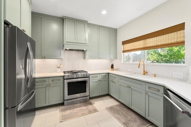 5701 Sunset Rdg, Austin, TX 78735 - kitchen with stainless steel appliances, green cabinets, decorative backsplash, light countertops, and light tile patterned floors