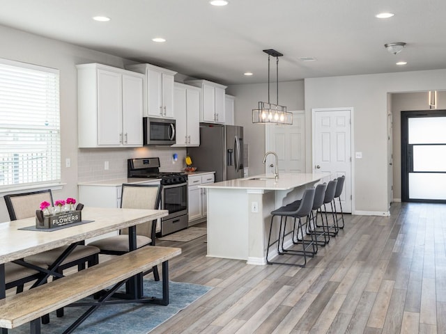 453 Arrowhead Vine St, Leander, TX 78641 - kitchen with stainless steel appliances, a center island with sink, recessed lighting, a kitchen bar, and light wood finished floors