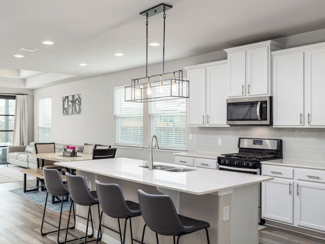 453 Arrowhead Vine St, Leander, TX 78641 - kitchen with appliances with stainless steel finishes, wood finished floors, a center island with sink, backsplash, and recessed lighting
