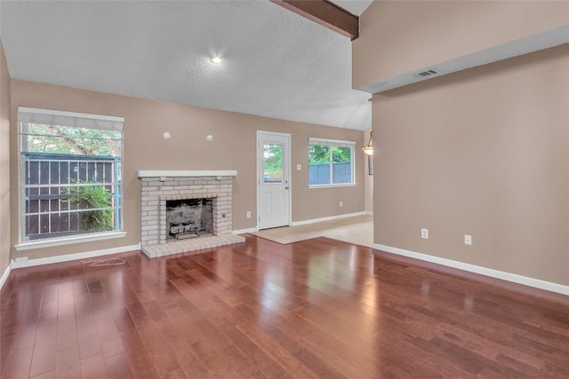 1028 Verbena Dr Unit 1144, Austin, TX 78750 - unfurnished living room featuring wood finished floors, a brick fireplace, and vaulted ceiling