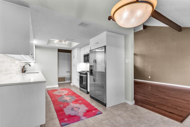 1028 Verbena Dr Unit 1144, Austin, TX 78750 - kitchen featuring appliances with stainless steel finishes, white cabinets, light tile patterned floors, light countertops, and a raised ceiling