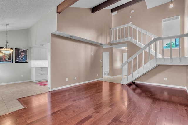 1028 Verbena Dr Unit 1144, Austin, TX 78750 - unfurnished living room with wood finished floors, high vaulted ceiling, stairs, and beam ceiling