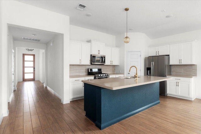 8213 Spire Vw, Austin, TX 78744 - kitchen featuring stainless steel appliances, tasteful backsplash, light countertops, a kitchen island with sink, and white cabinets