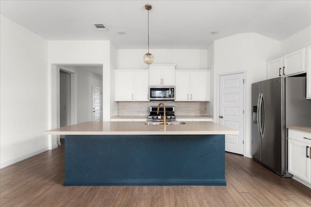 8213 Spire Vw, Austin, TX 78744 - kitchen featuring appliances with stainless steel finishes, backsplash, a kitchen island with sink, wood finished floors, and light countertops