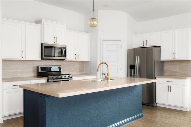 8213 Spire Vw, Austin, TX 78744 - kitchen with appliances with stainless steel finishes, a kitchen island with sink, white cabinetry, backsplash, and light countertops