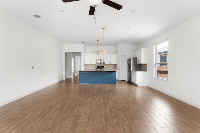 8213 Spire Vw, Austin, TX 78744 - kitchen with stainless steel appliances, decorative backsplash, a ceiling fan, white cabinets, and open floor plan