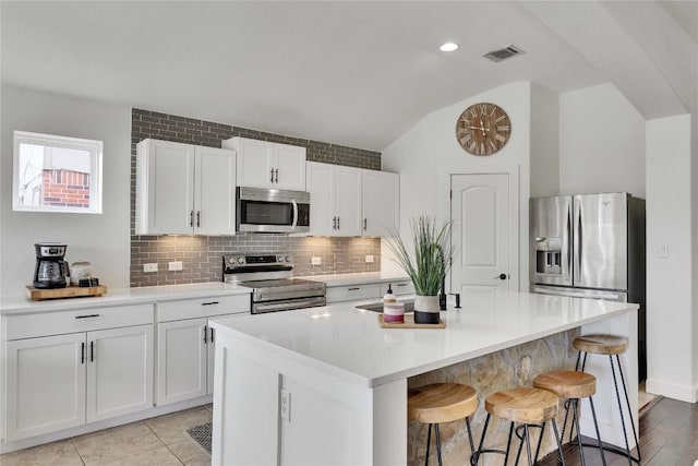 239 Holman Path, Hutto, TX 78634 - kitchen with appliances with stainless steel finishes, vaulted ceiling, a breakfast bar, tasteful backsplash, and an island with sink