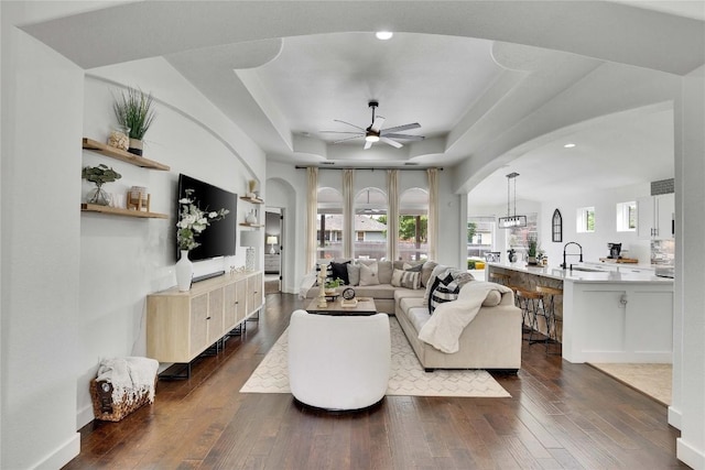 239 Holman Path, Hutto, TX 78634 - living area featuring a raised ceiling, ceiling fan, dark wood finished floors, arched walkways, and recessed lighting