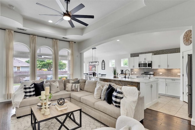 239 Holman Path, Hutto, TX 78634 - living room featuring a raised ceiling, arched walkways, ceiling fan, light wood-style flooring, and recessed lighting