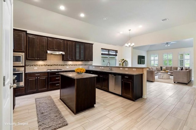 2520 Milan Meadows Dr, Leander, TX 78641 - kitchen with stainless steel appliances, lofted ceiling, under cabinet range hood, a peninsula, and a chandelier