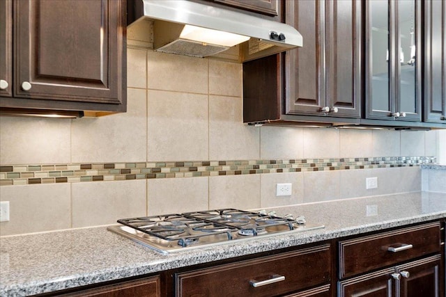 2520 Milan Meadows Dr, Leander, TX 78641 - kitchen with stainless steel gas stovetop, dark brown cabinets, under cabinet range hood, and backsplash