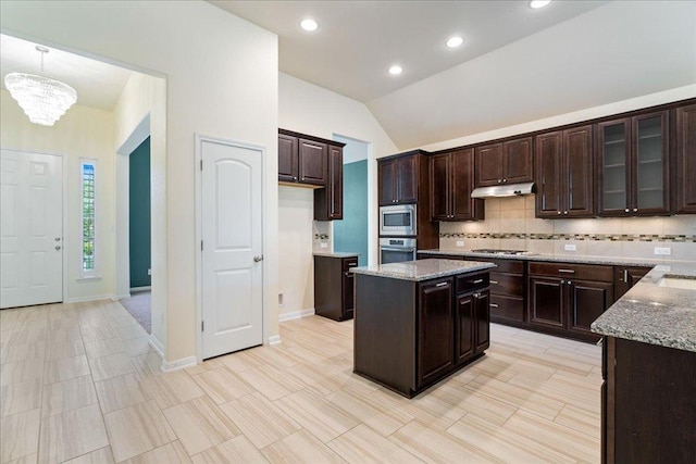 2520 Milan Meadows Dr, Leander, TX 78641 - kitchen featuring appliances with stainless steel finishes, under cabinet range hood, vaulted ceiling, tasteful backsplash, and a kitchen island