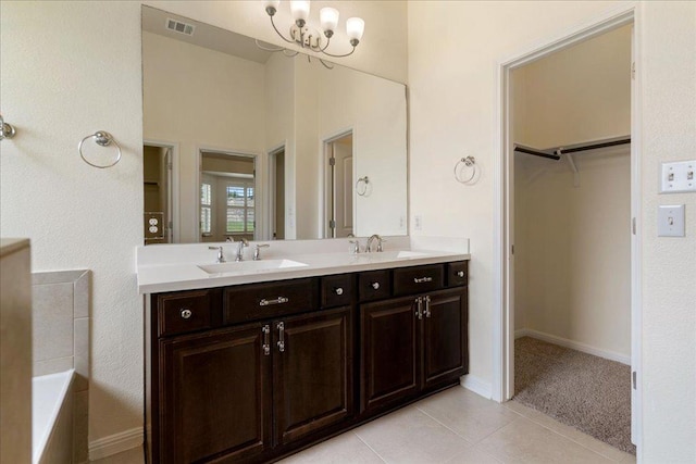 2520 Milan Meadows Dr, Leander, TX 78641 - bathroom featuring double vanity, a walk in closet, a chandelier, tile patterned floors, and a bath