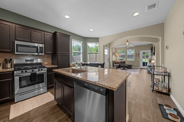 1420 Anhalt Dr Unit 50B, Pflugerville, TX 78660 - kitchen featuring appliances with stainless steel finishes, arched walkways, dark wood-type flooring, tasteful backsplash, and light stone counters