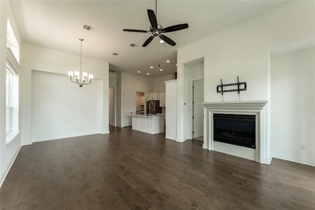 152 Limestone Dr, Georgetown, TX 78628 - unfurnished living room with a chandelier, ceiling fan, a glass covered fireplace, dark wood-style floors, and recessed lighting