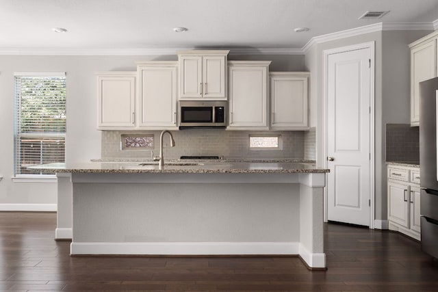 103 County Road 180 Unit 35, Leander, TX 78641 - kitchen with appliances with stainless steel finishes, light stone countertops, a kitchen island with sink, dark wood-style floors, and tasteful backsplash