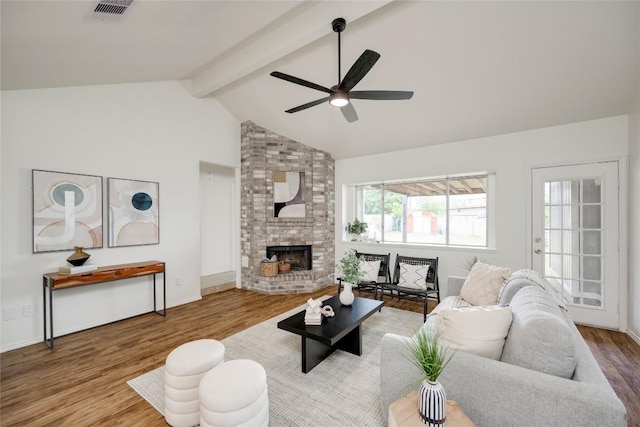 16302 Bates Cv, Pflugerville, TX 78660 - living room with ceiling fan, wood finished floors, beamed ceiling, a brick fireplace, and high vaulted ceiling