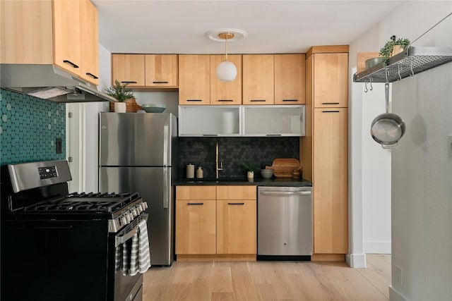 6806 Syracuse Cv, Austin, TX 78723 - kitchen featuring stainless steel appliances, under cabinet range hood, dark countertops, light wood-type flooring, and decorative backsplash