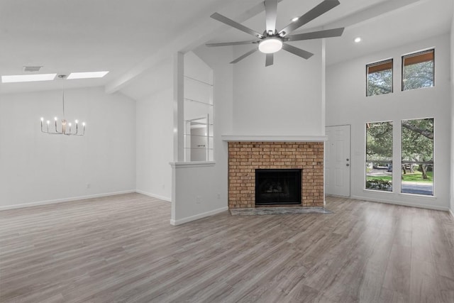 7907 Tealwood Trl, Austin, TX 78731 - unfurnished living room featuring high vaulted ceiling, a chandelier, a skylight, wood finished floors, and a fireplace