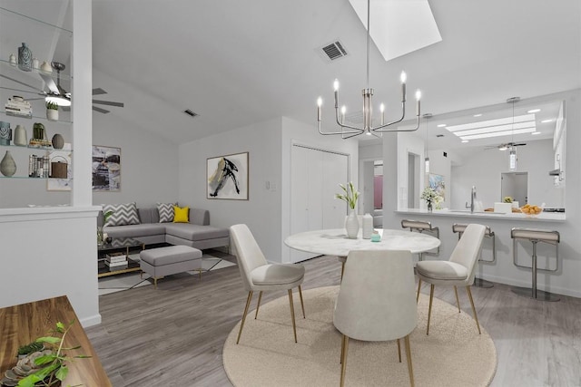 7907 Tealwood Trl, Austin, TX 78731 - dining space with a skylight, ceiling fan, light wood-style flooring, vaulted ceiling, and a chandelier
