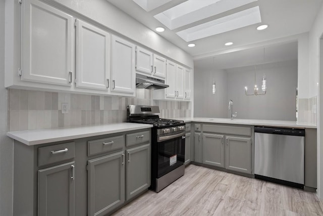 7907 Tealwood Trl, Austin, TX 78731 - kitchen with stainless steel appliances, under cabinet range hood, gray cabinetry, a skylight, and light countertops