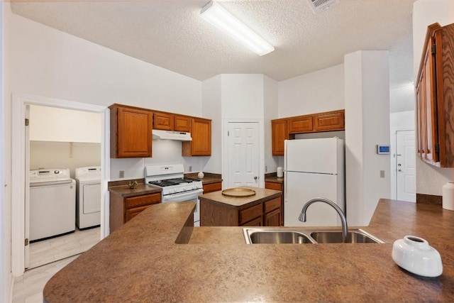 7806 Vail Valley Dr, Austin, TX 78749 - kitchen featuring white appliances, separate washer and dryer, under cabinet range hood, brown cabinets, and a textured ceiling