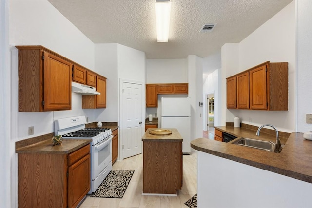 7806 Vail Valley Dr, Austin, TX 78749 - kitchen featuring white appliances, a textured ceiling, under cabinet range hood, dark countertops, and a peninsula