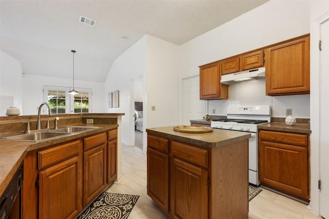 7806 Vail Valley Dr, Austin, TX 78749 - kitchen featuring gas range gas stove, dark countertops, under cabinet range hood, vaulted ceiling, and brown cabinets
