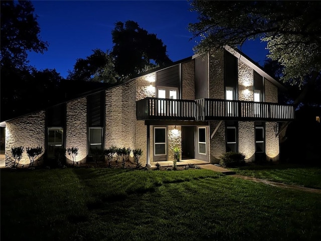 10006 Mandeville Cir, Austin, TX 78750 - back of house at twilight featuring stone siding, a yard, and a balcony
