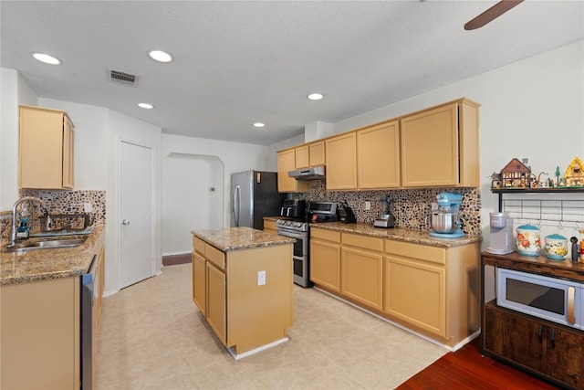 6005 La Mesa St, Leander, TX 78645 - kitchen with appliances with stainless steel finishes, a kitchen island, tasteful backsplash, under cabinet range hood, and light stone counters