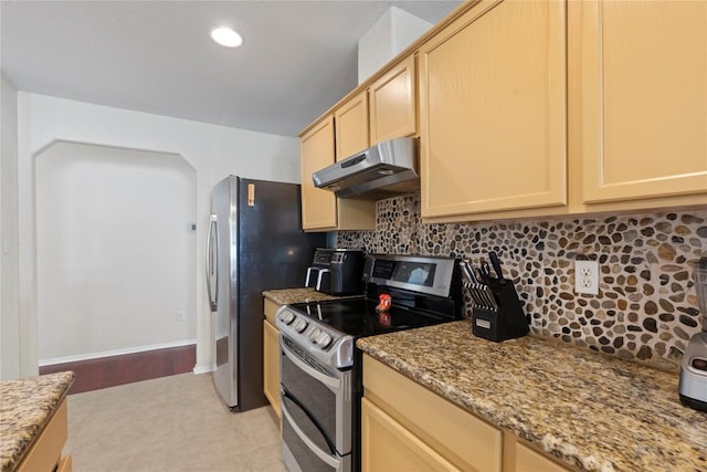 6005 La Mesa St, Leander, TX 78645 - kitchen featuring range with two ovens, under cabinet range hood, tasteful backsplash, light stone counters, and arched walkways