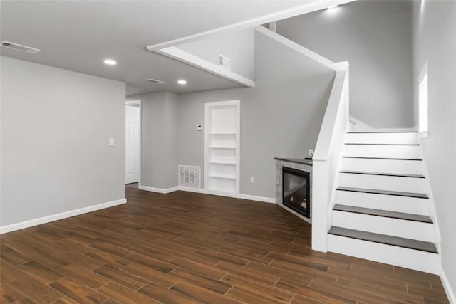 106 Harper Dr, Bastrop, TX 78602 - unfurnished living room featuring dark wood-style floors, stairway, recessed lighting, and a glass covered fireplace