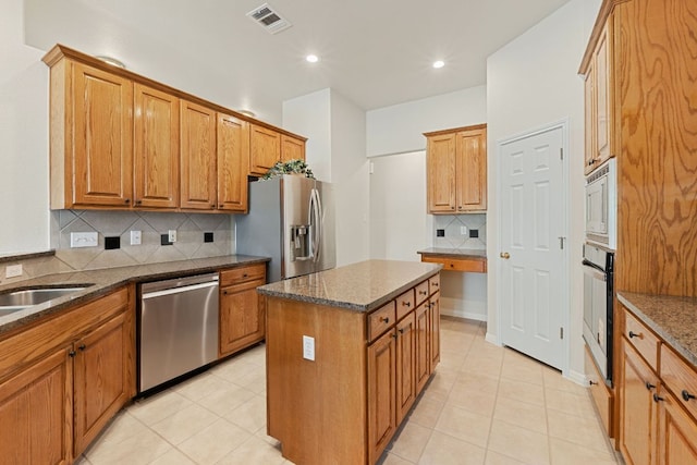 2700 Dagama Ct, Cedar Park, TX 78613 - kitchen with appliances with stainless steel finishes, decorative backsplash, a center island, dark stone counters, and brown cabinets