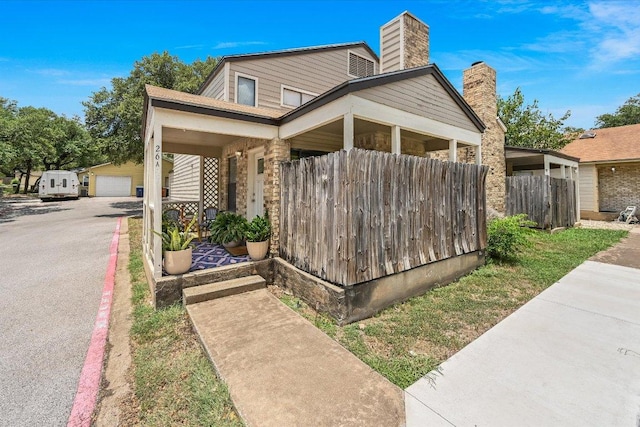 7825 Beauregard Cir Unit 26, Austin, TX 78745 - view of side of property featuring a chimney, a garage, an outbuilding, and a porch