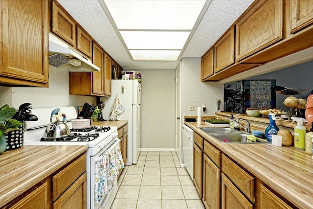 7825 Beauregard Cir Unit 26, Austin, TX 78745 - kitchen featuring white appliances, under cabinet range hood, light tile patterned floors, brown cabinetry, and a textured ceiling