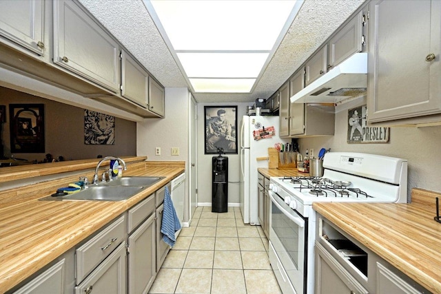 7825 Beauregard Cir Unit 26, Austin, TX 78745 - kitchen with white gas range oven, under cabinet range hood, butcher block countertops, light tile patterned floors, and gray cabinets